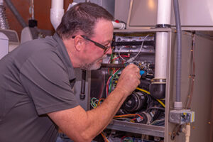Service man performing Manasquan heating repair to a furnace