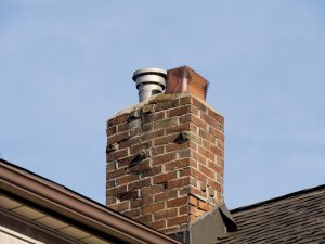 Old brick chimney with crumbling mortar joints and a deteriorated crown, a common repair for chimney service in Hazlet